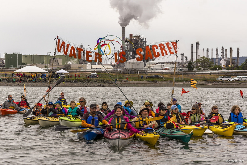 Small_800px_Water_is_Sacred_during_Indigenous_Day_Flotilla_at_Break_Free_PNW_2016_Photo_taken_by_John_Duffy_27104327905_dac087b675_c.jpg