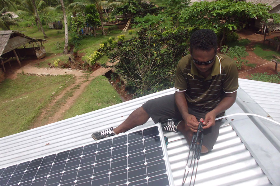 Holland Sikou installing solar panels on the roof of a school in Solomon Islands.