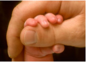 photo of infant hand grasping adult thumb