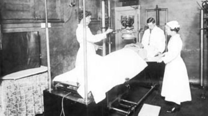 photo of patient under instrument with 3 workers at close range