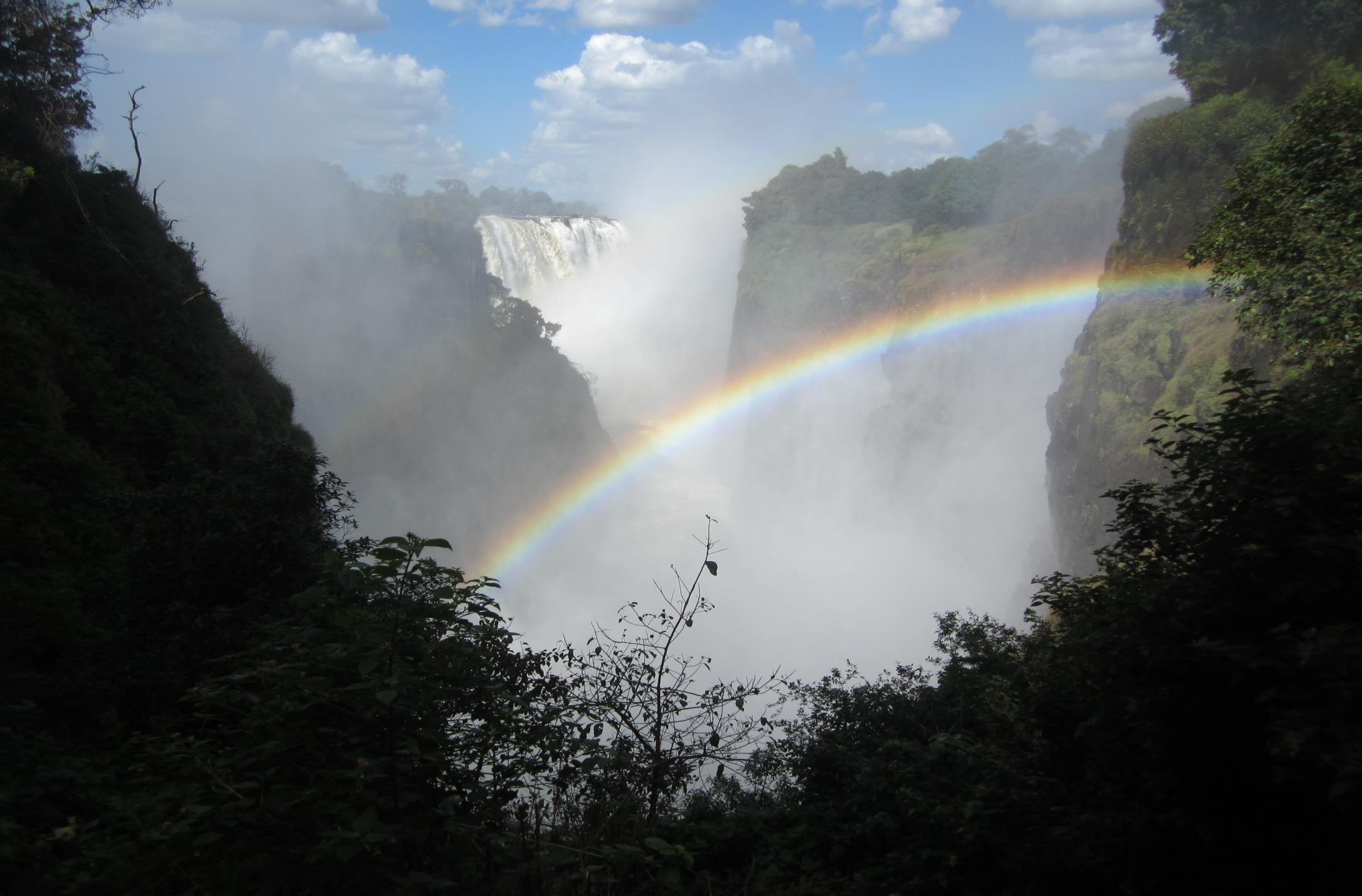 photo of a rainbow in front of distant Victoria Falls