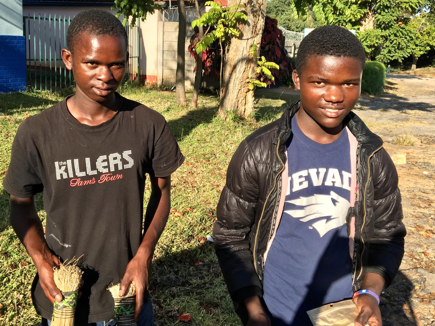 photo of teenagers holding brooms and electronics
