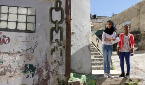 Two Palestinian girls stand on the steps of the Not To Forget Society’s building in Jenin refugee camp, West Bank