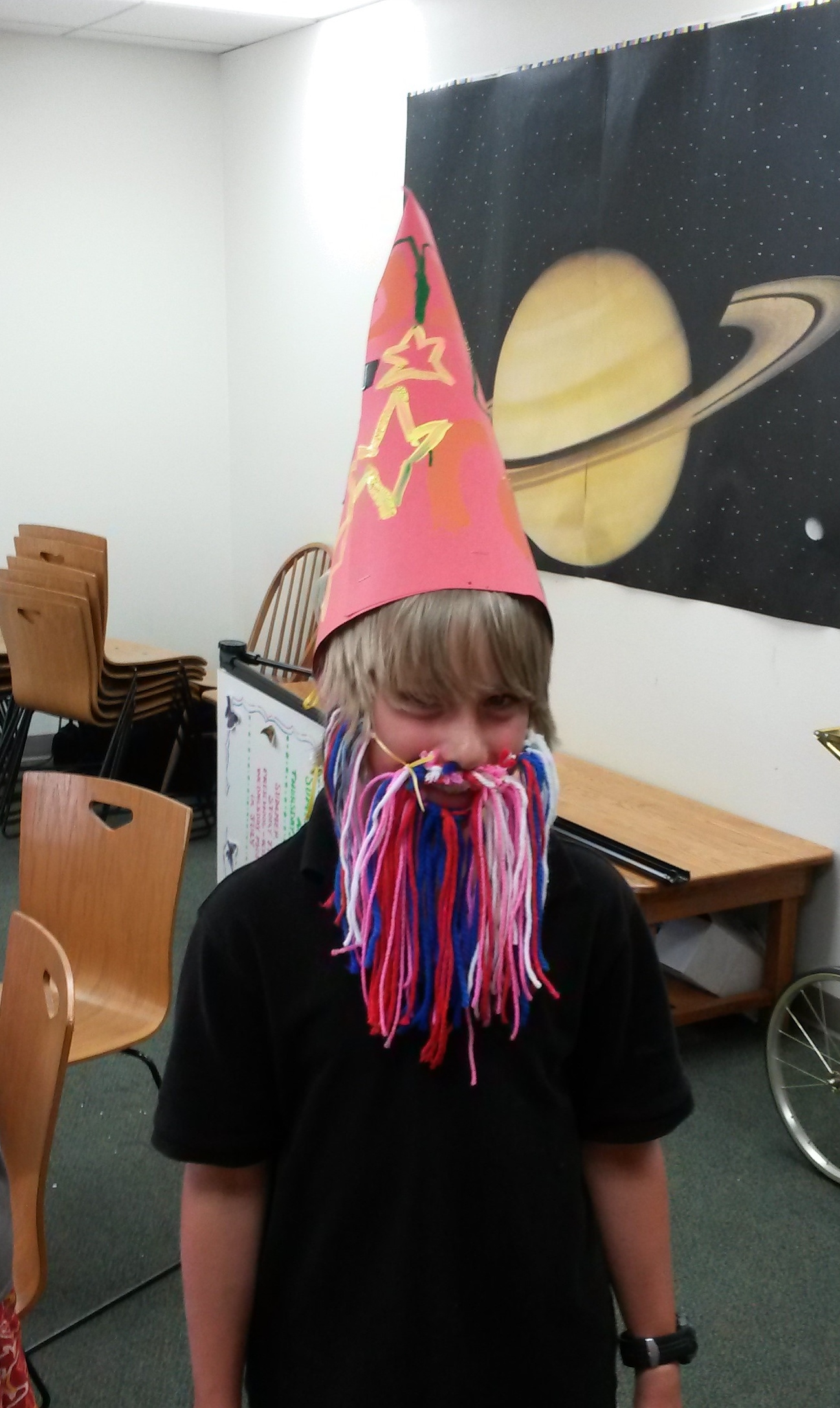 Child wearing cone hat and yarn beard