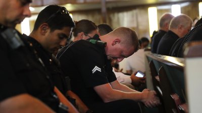 1607 - DAI - FOX - Police Officer Bows Head in Prayer