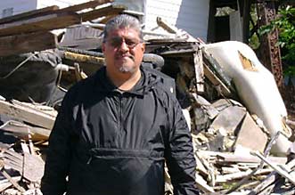 Luis J. Rodriguez in front of what was once someone's home