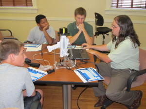 Instructor Jason Church (far right) explains the pXRF (portable x-ray fluorescence) tool to students. Image provided by Jason Church.