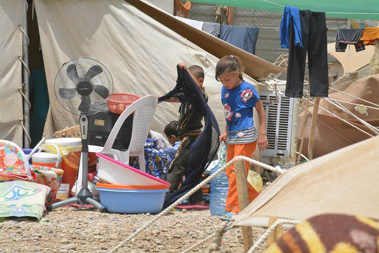 Children recently displaced from Ramadi set out to organize household goods given to their family, just outside their tent.