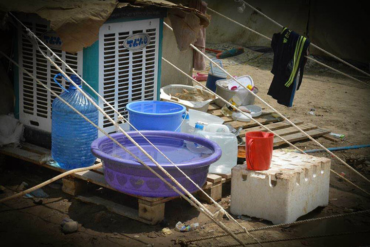 The make-shift kitchen of families recently displaced from Ramadi in Iraq features plastic bins and water bottles perched on old shipping pallets.