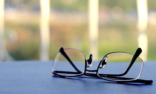 A pair of glasses resting on a blue surface