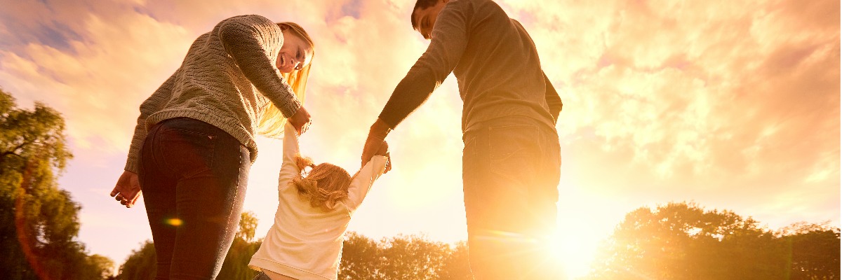 Parents playing with child in a field.