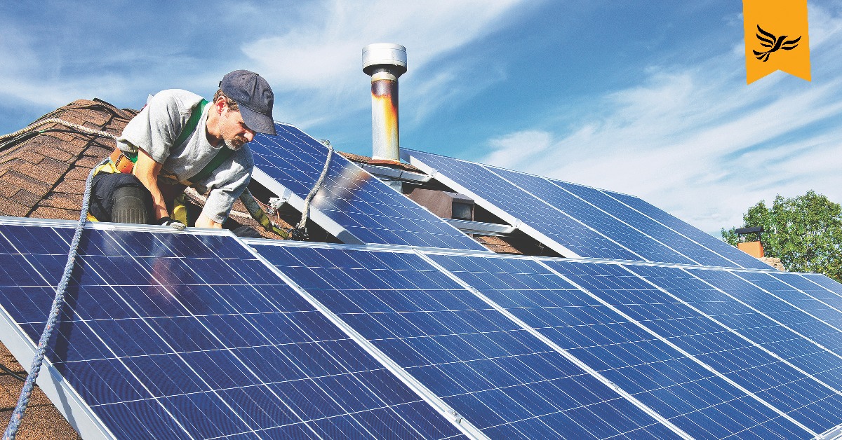 A worker fitting solar panels on a roof.