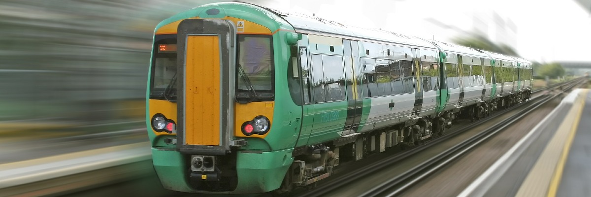 A Southern Rail train passing through a station at speed.