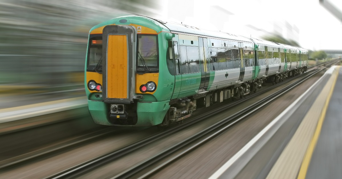 A Southern Rail train passing through a station at speed.