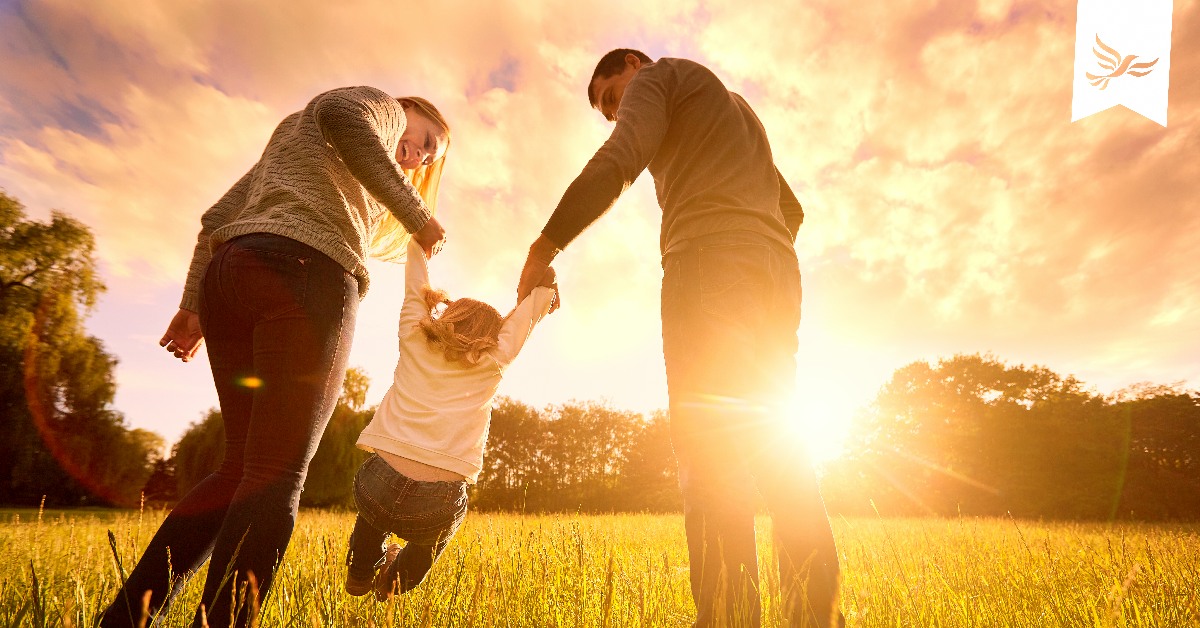 Parents playing with child in a field.