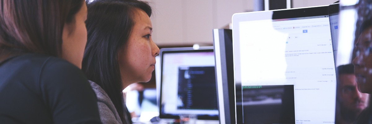 Two women looking at computer screens in an office.