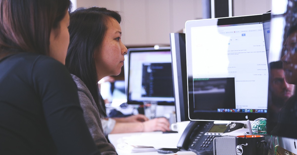Two women looking at computer screens in an office.