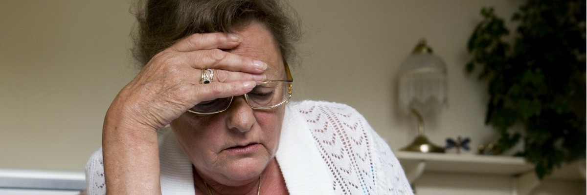 Worried-looking woman with her hand to her head.