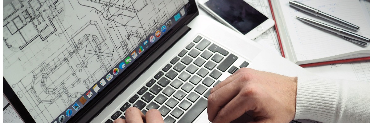 Plans on Macbook screen, hands operating laptop.
