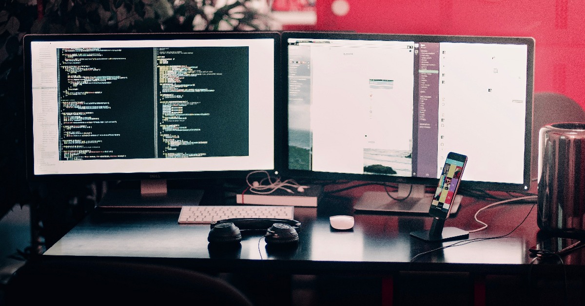 Two computer screens at a desk.