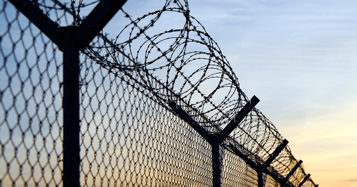 A metal fence topped with barbed wire