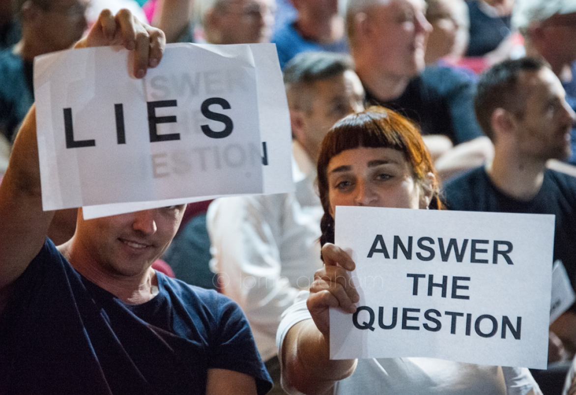 Residents holding signs saying Lies & Answer the Question at WestCONnex info evening
