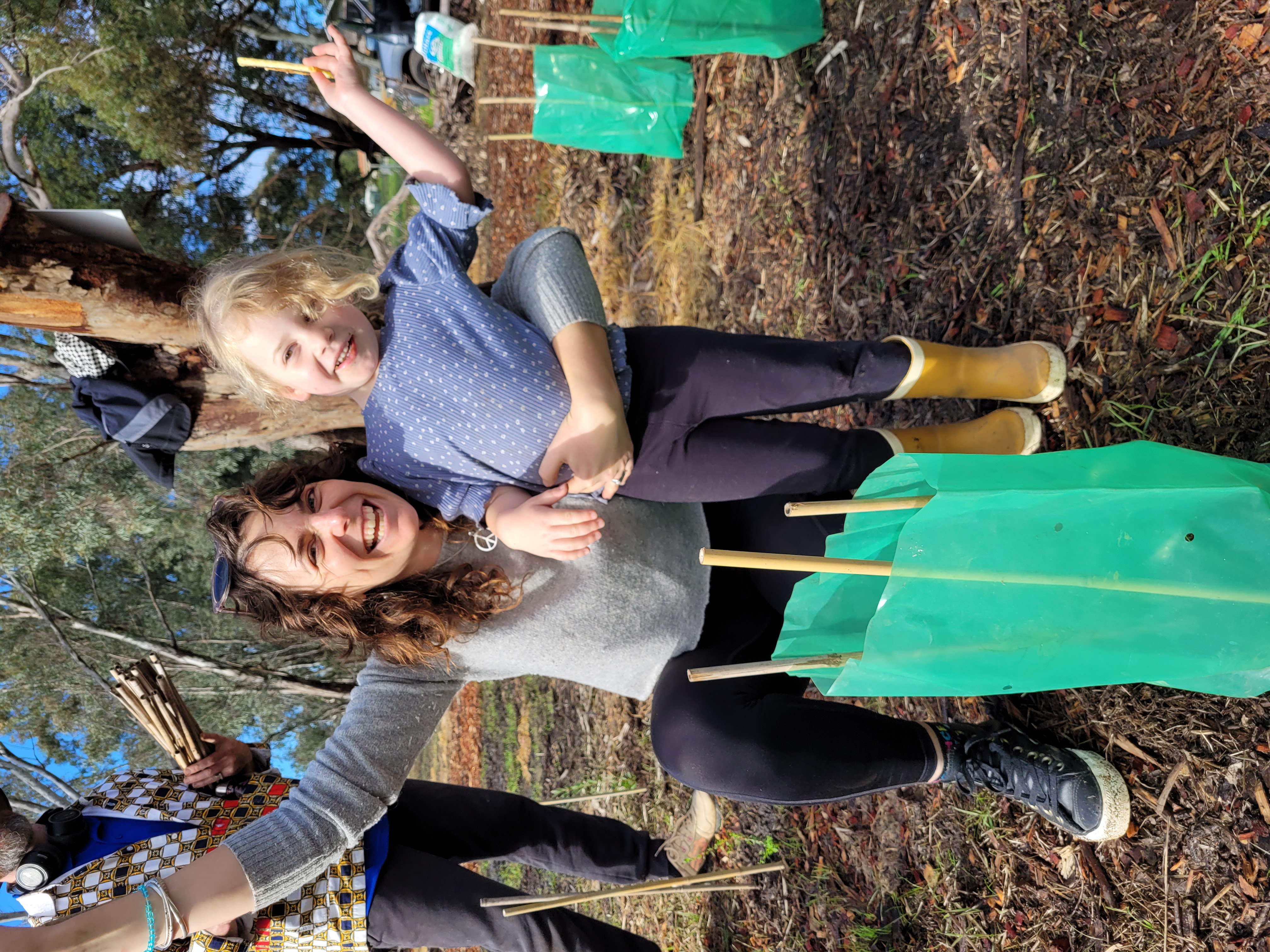 Wilderness Society team member Katie with little niece celebrating a newly planted sleedling protected with a plastic tree guard.