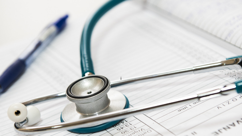 A stethoscope sitting on tope of a notepad and pen